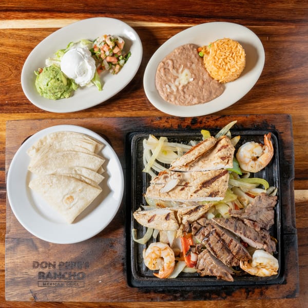 Don Pepe's Rancho Mexican Grill fajitas with chicken, steak, shrimp, tortillas, rice, beans, and toppings.